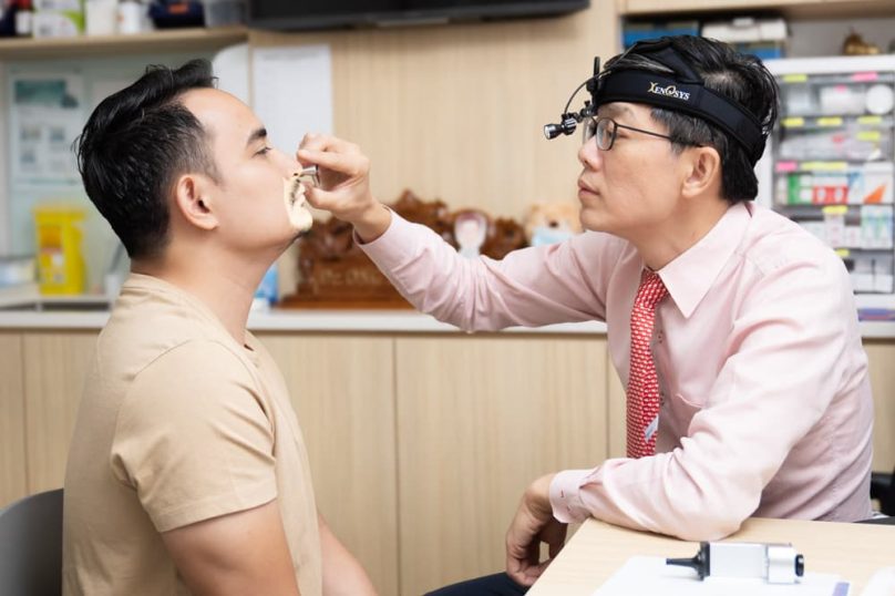 ENT specialist performing nasal examination on patient to assess septal deviation