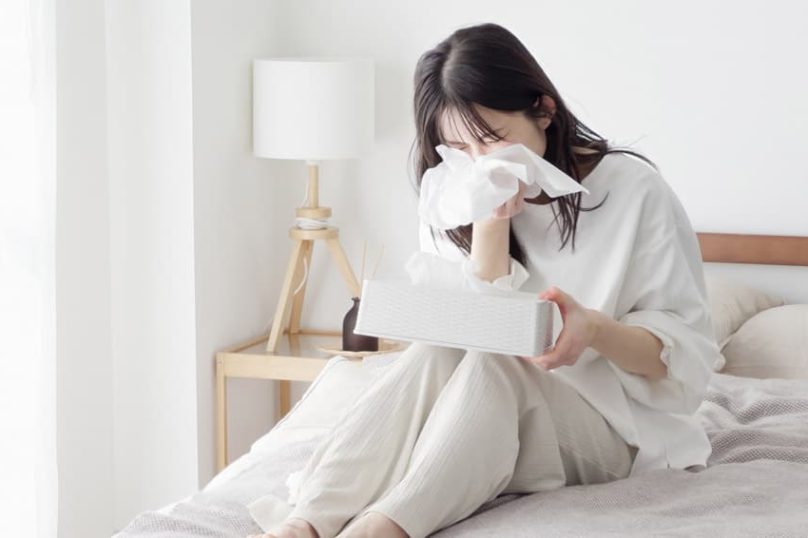 Woman experiencing sneezing and nasal irritation from allergic rhinitis