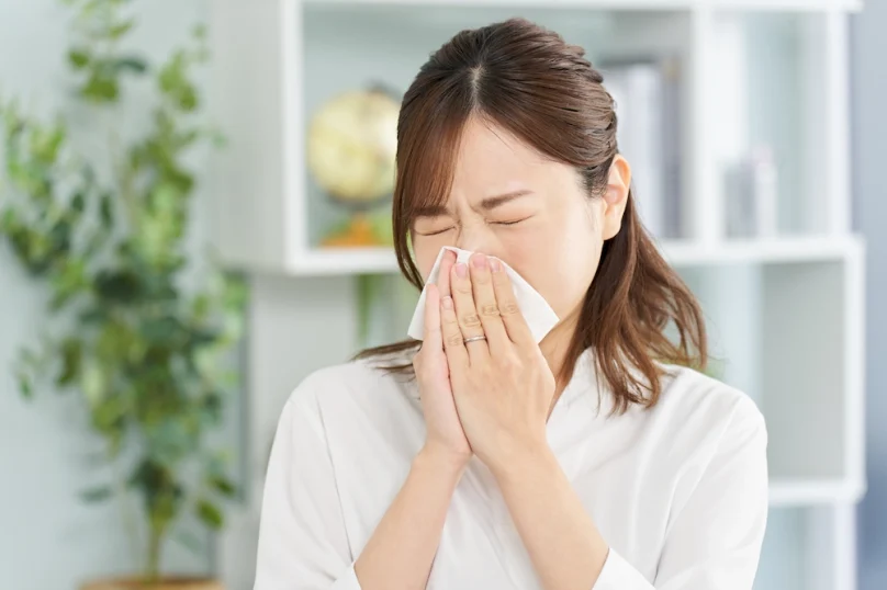 Image of an Asian woman blowing her nose into a handkerchief